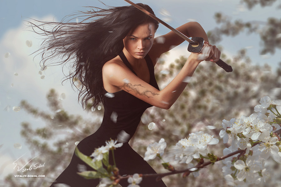 Beautiful Brunette with katana sword in spring floral environment 