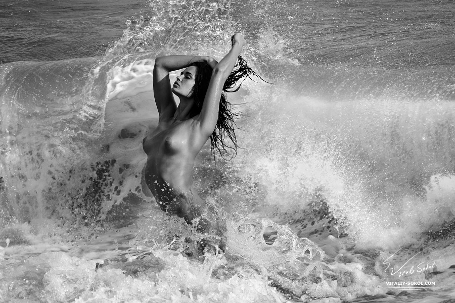 Beautiful Naked brunette in splashed waves in ocean